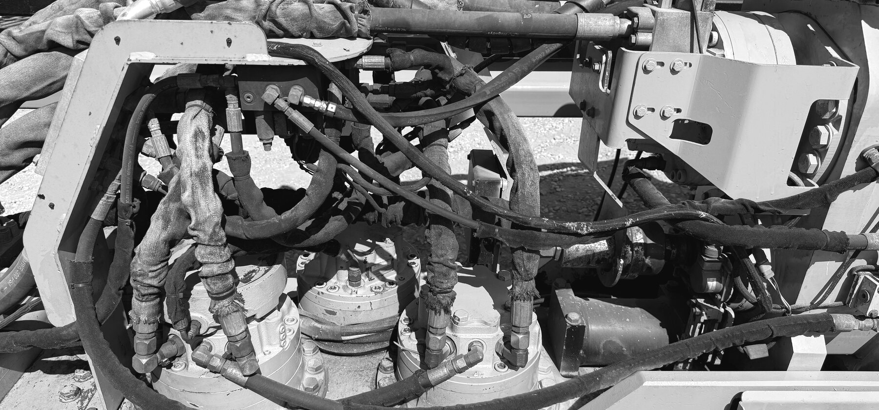 A dense cluster of hydraulic hoses and valves on a directional drill's rod-loading arm