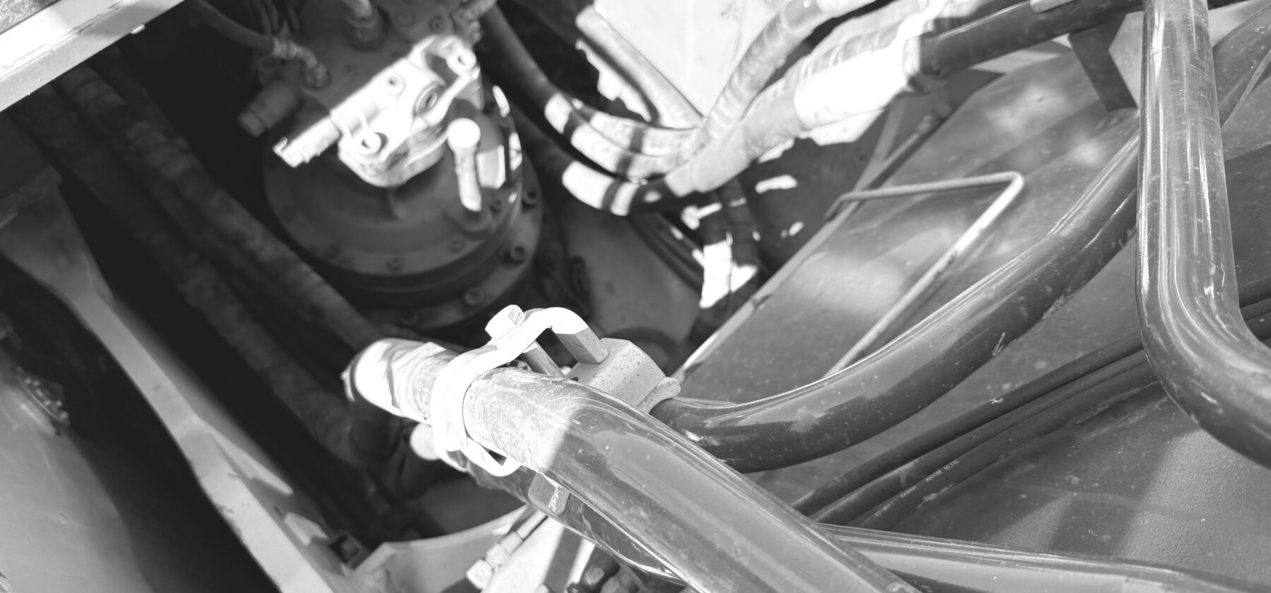 A cluster of hydraulic hoses and fittings routed through an excavator's upper works