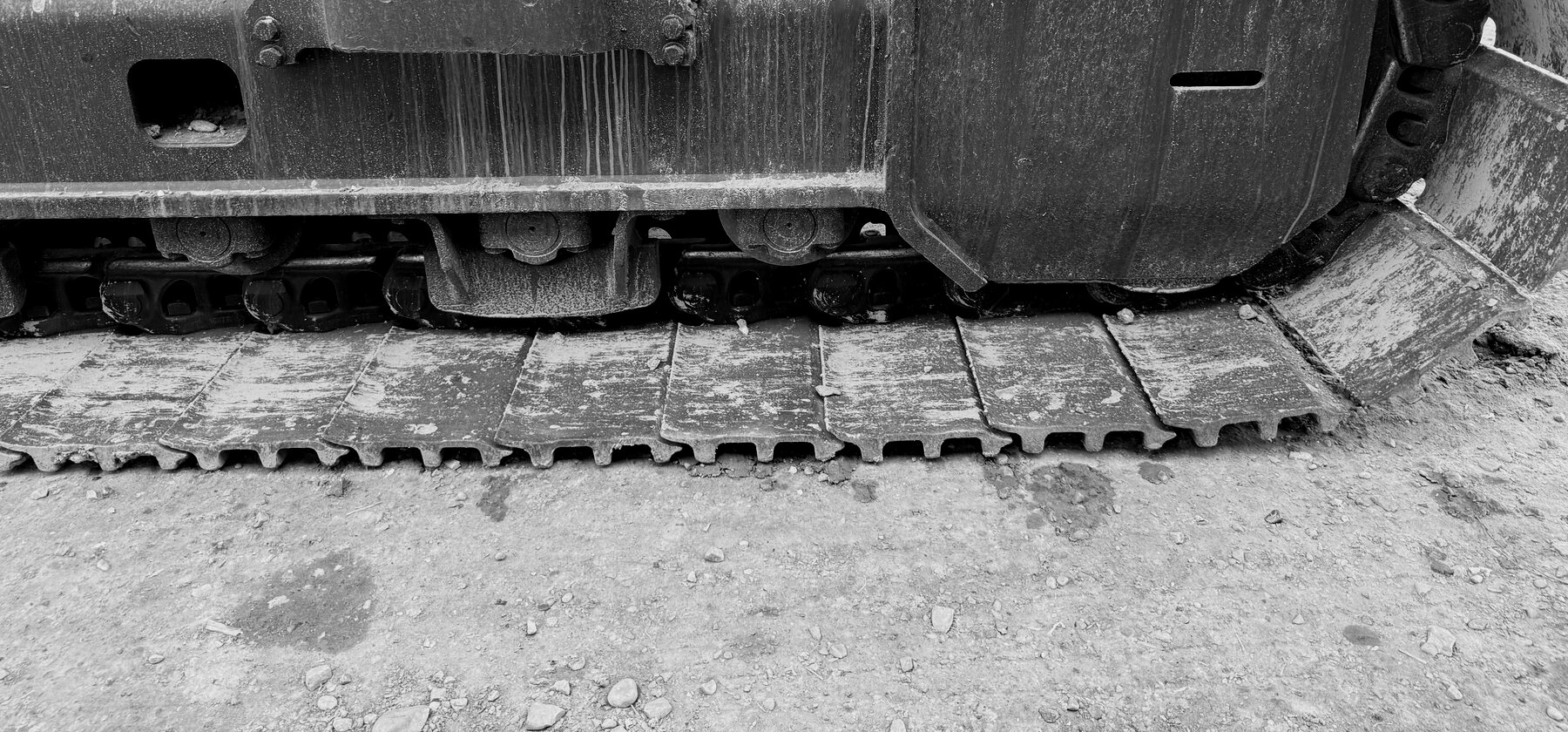 A dust-caked idler wheel and track chain on an excavator undercarriage