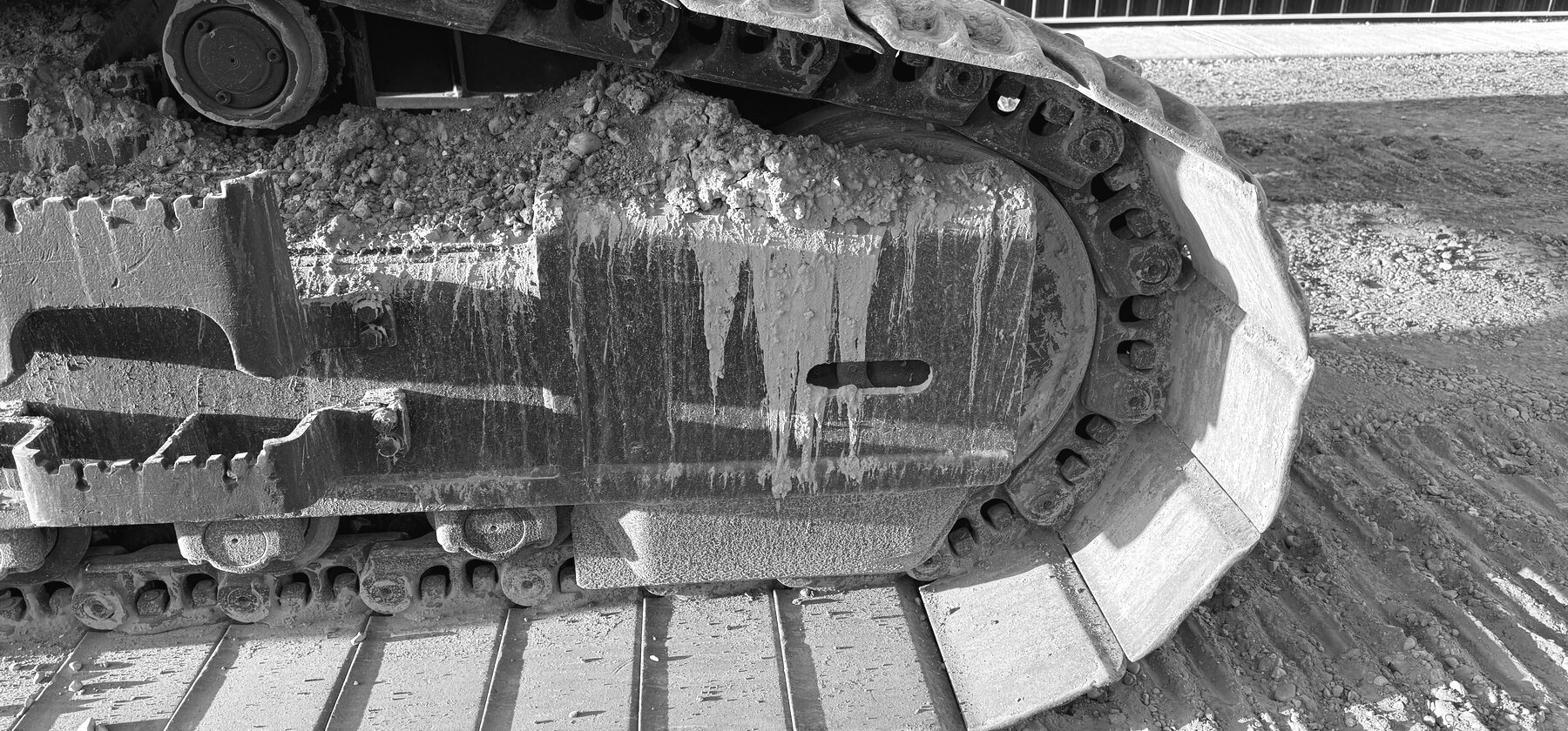 A worn steel track chain and roller on an excavator undercarriage