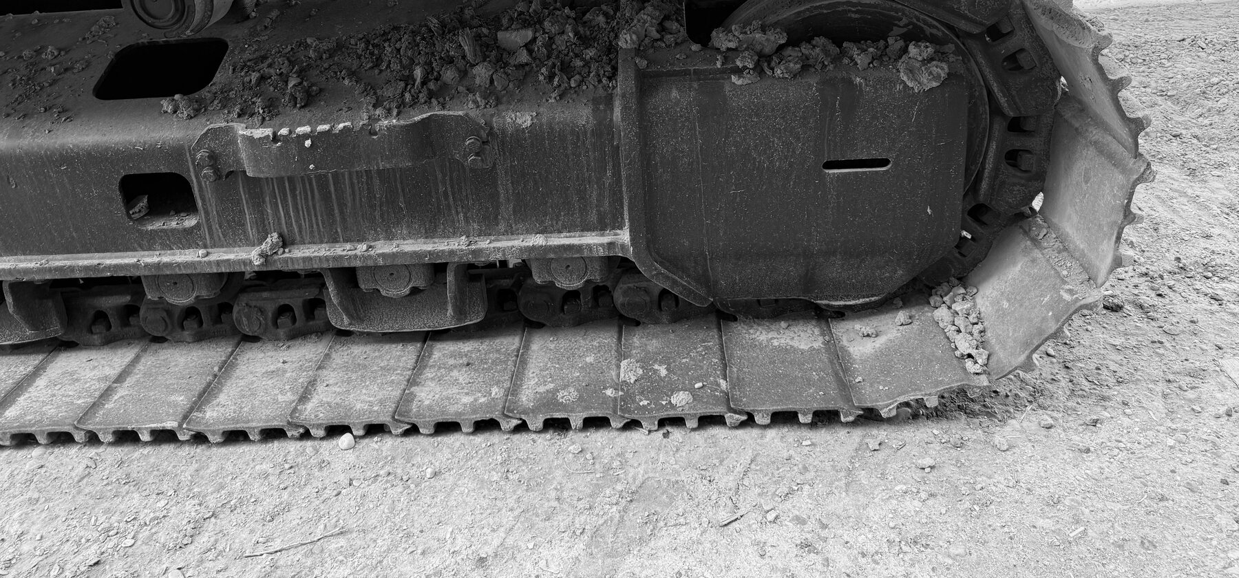 A mud-streaked track roller and drive sprocket on an excavator's undercarriage