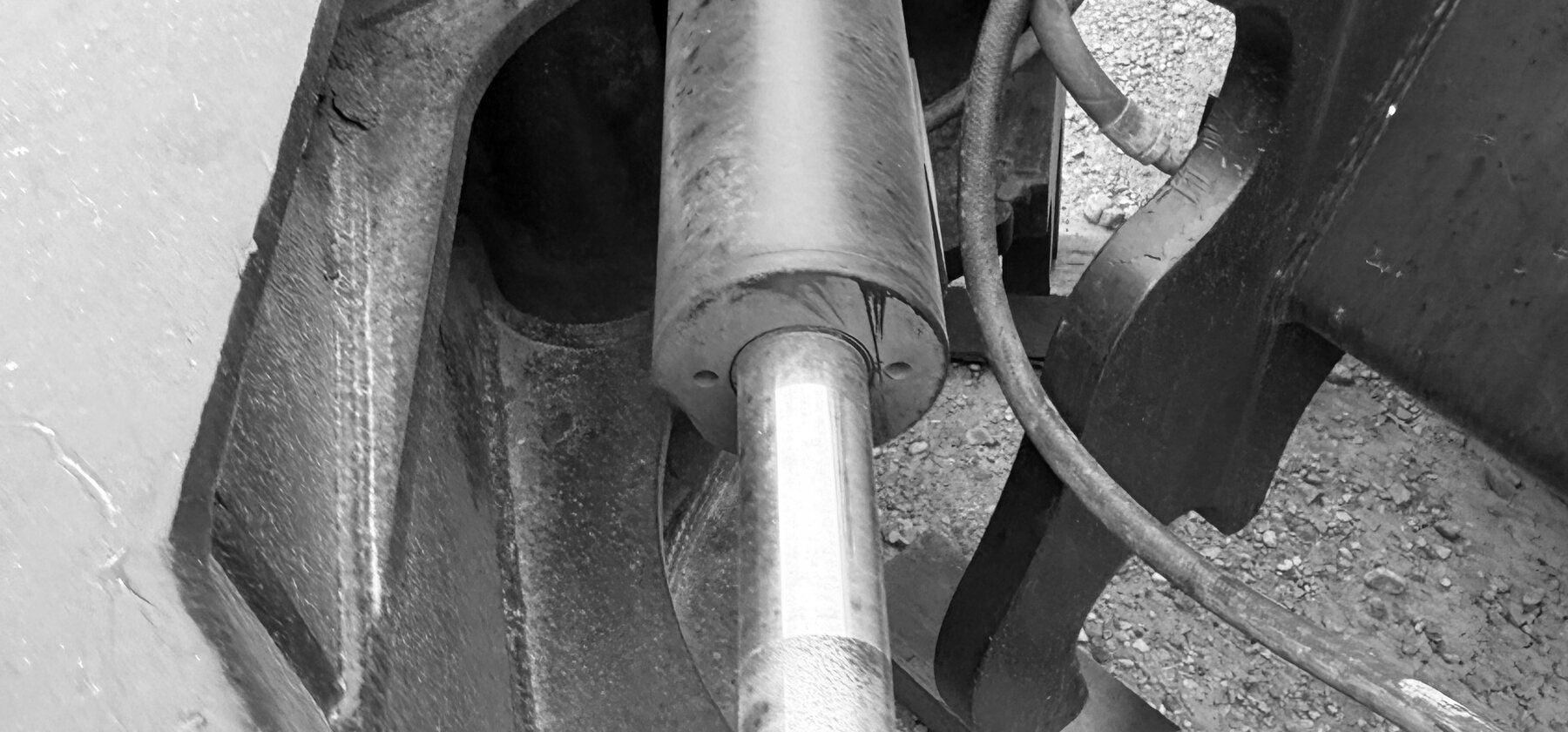 A hydraulic cylinder and pin joint inside a heavy attachment's linkage, wood cribbing stacked behind