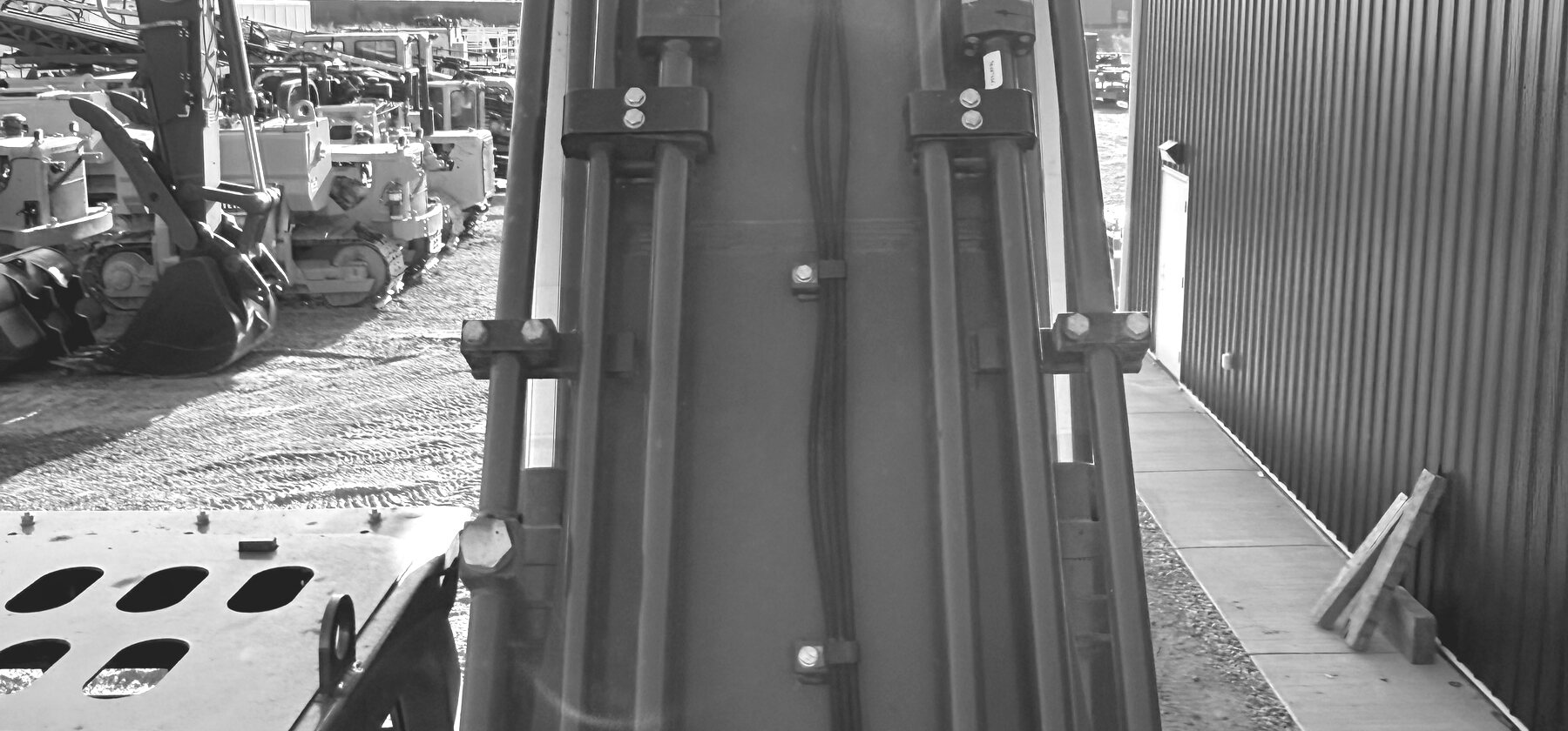 Hydraulic lines running the length of an excavator boom in strong sunlight