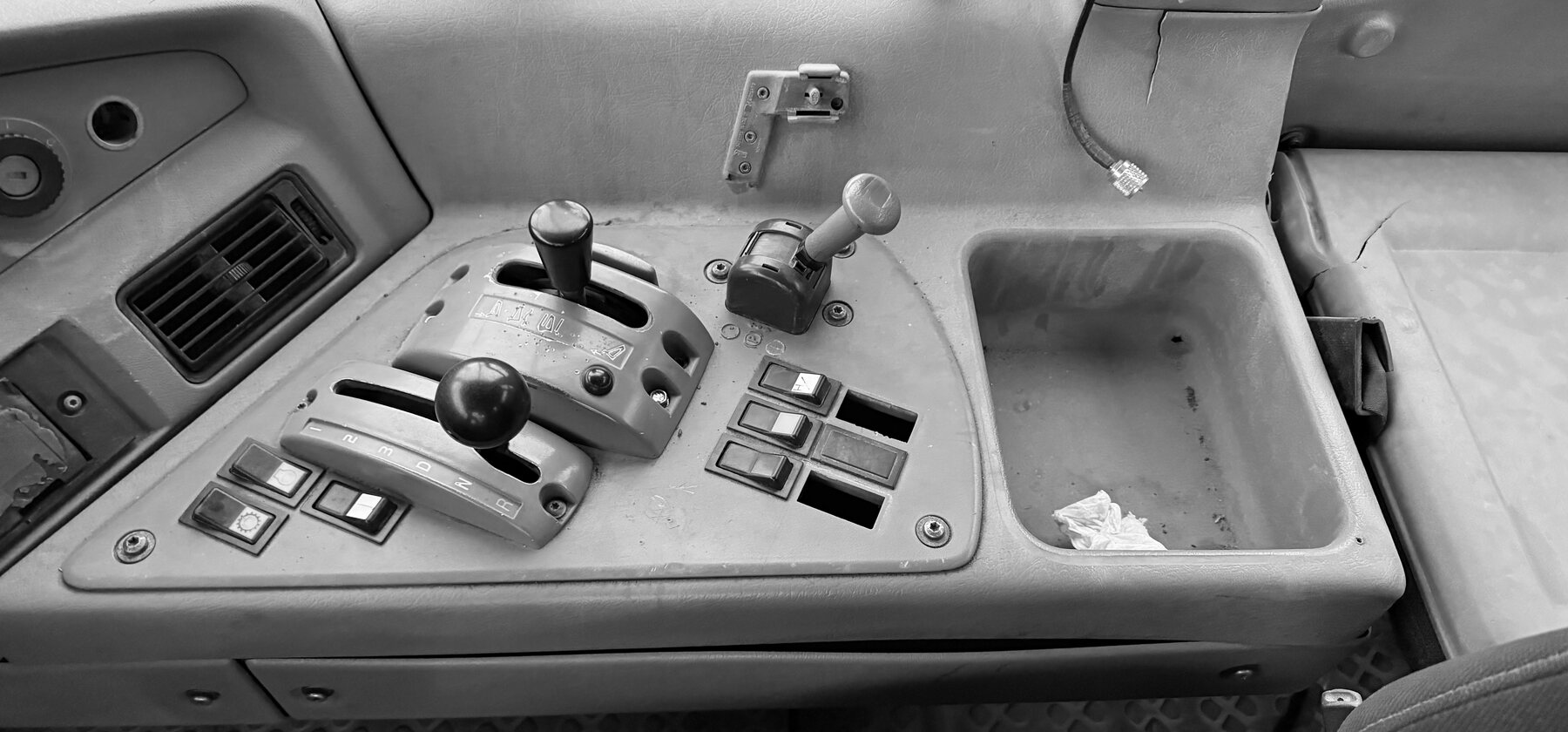 A gear shifter and switch console inside a rock truck cab