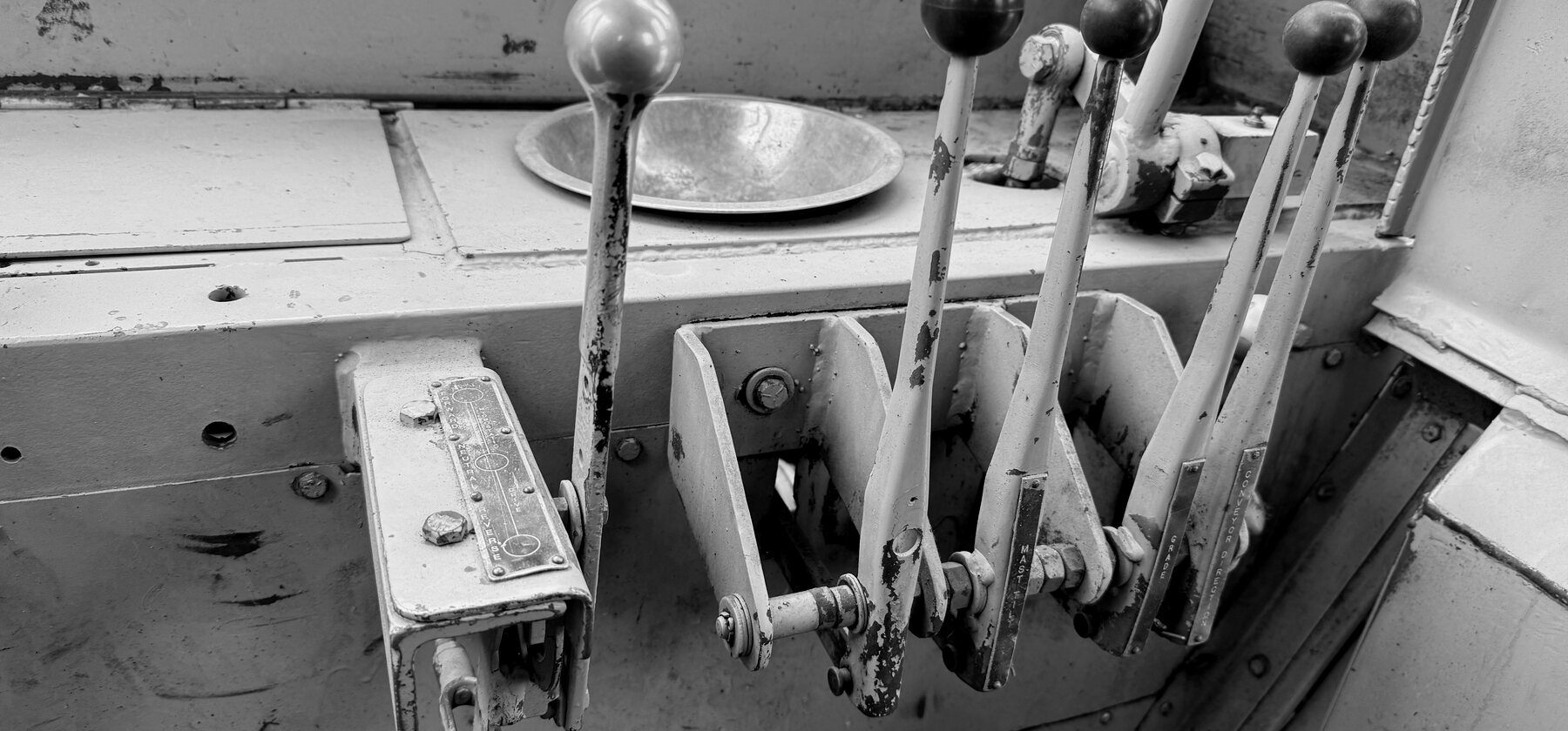 A row of hydraulic control levers on a trencher's console, labelled by function