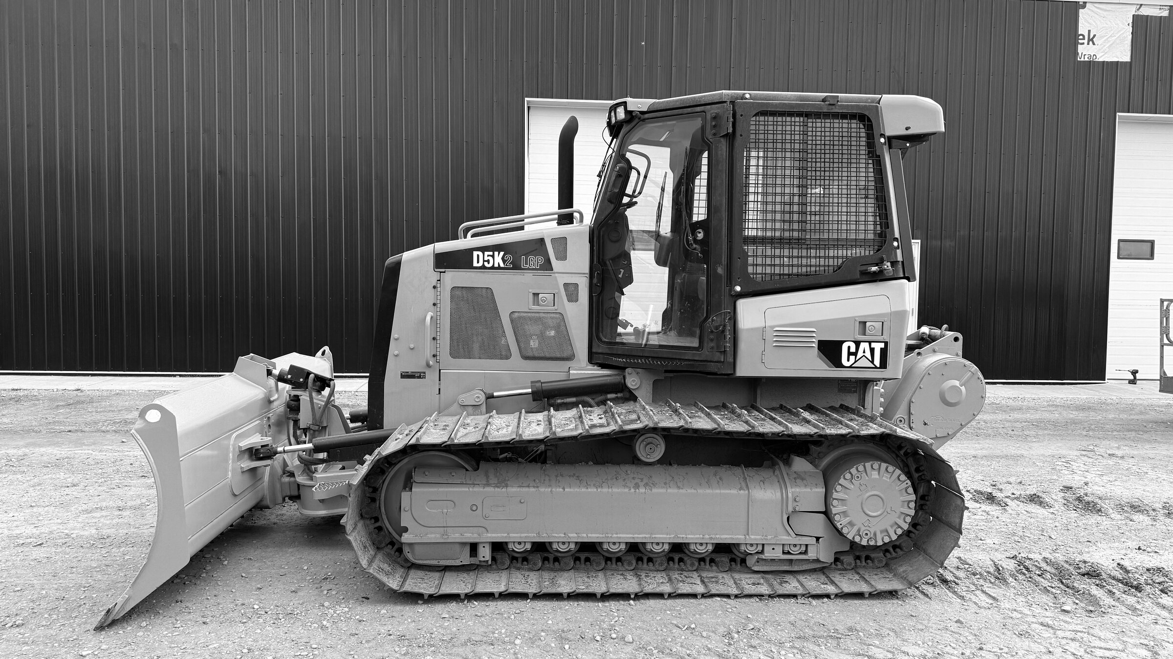 A tracked dozer standing side-on with its blade lowered to the ground