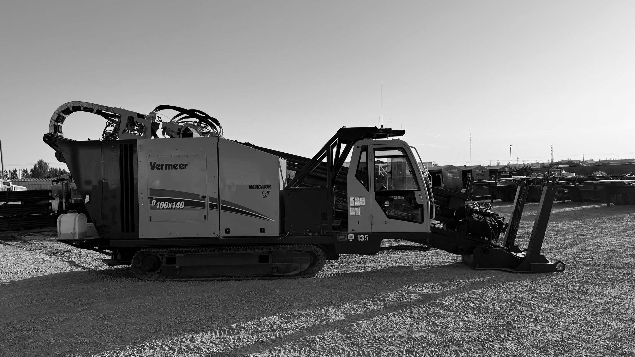 A tracked directional drill standing on a gravel pad, its carriage laid out behind it