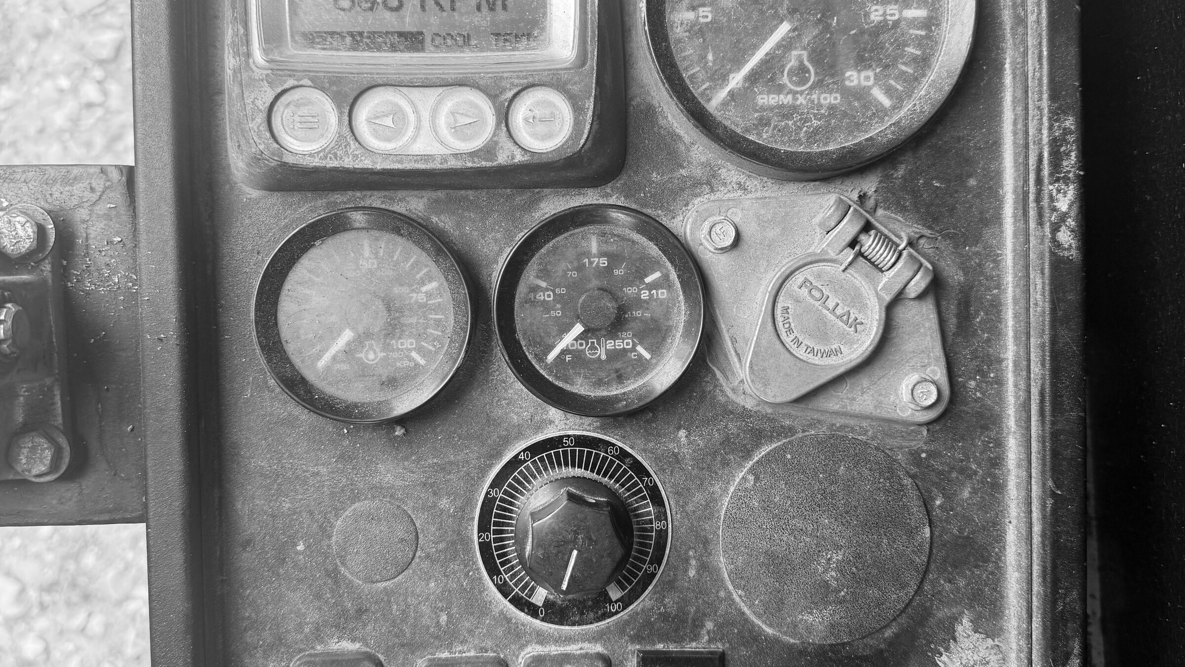 A machine's gauge cluster: an hour meter, dials and switches in a worn steel panel