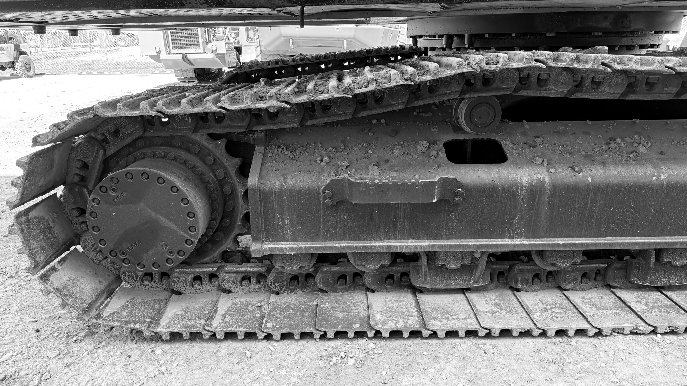 The full length of an excavator's track frame, chain and sprocket on gravel