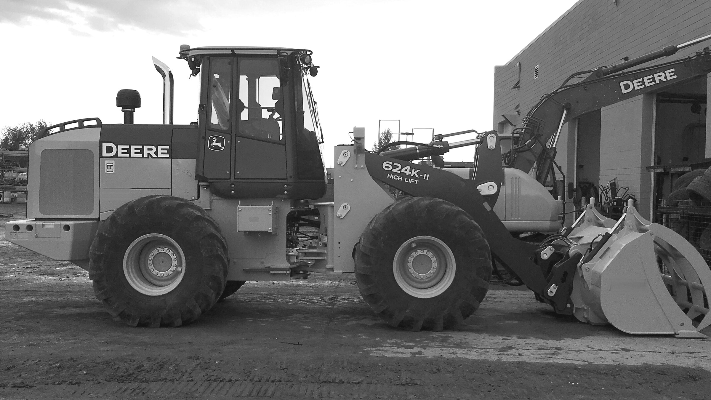 A wheel loader standing outside a shop with other machines behind it