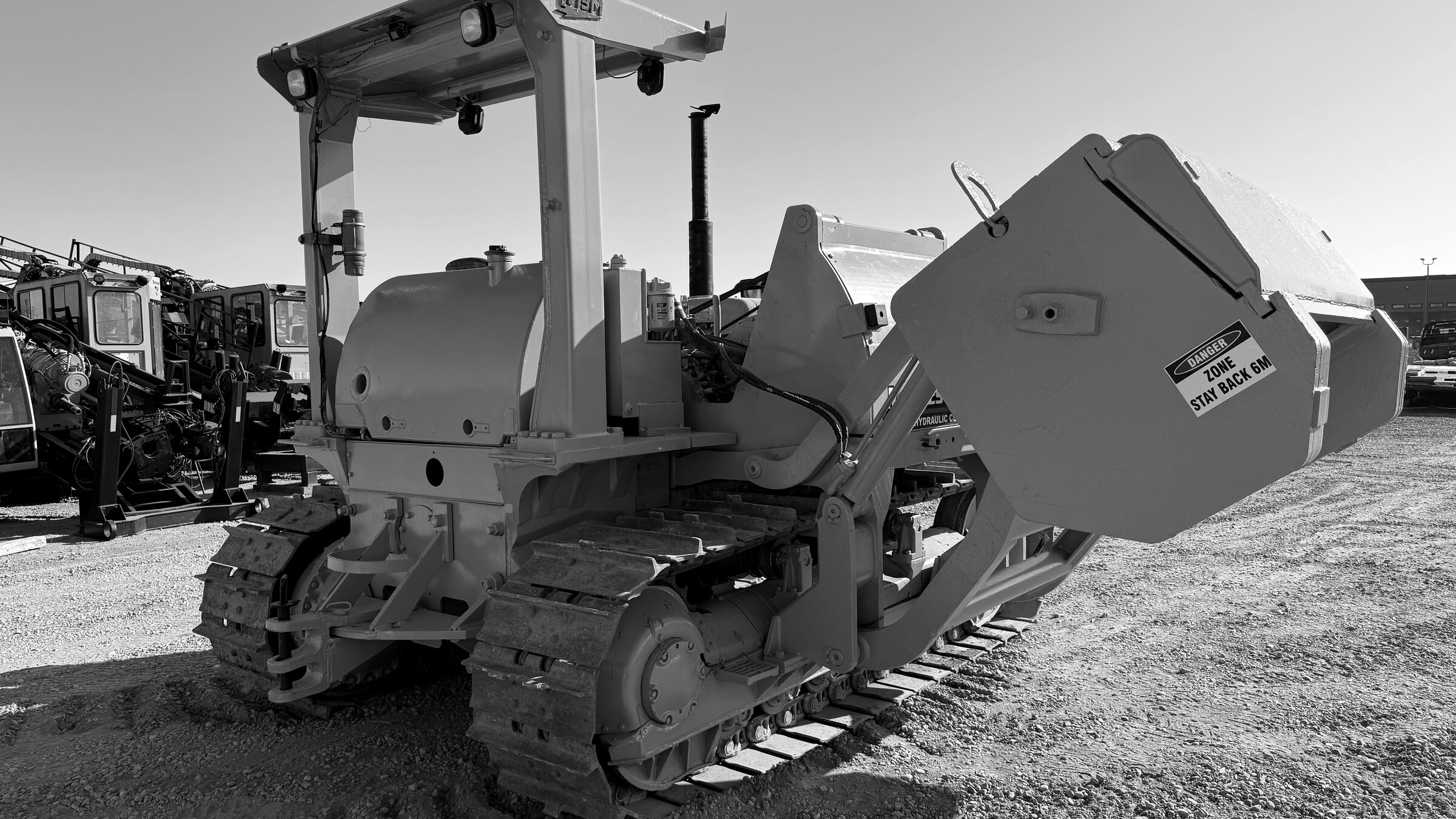 A tracked pipelayer seen low against the sky, boom overhead and tracks filling the frame