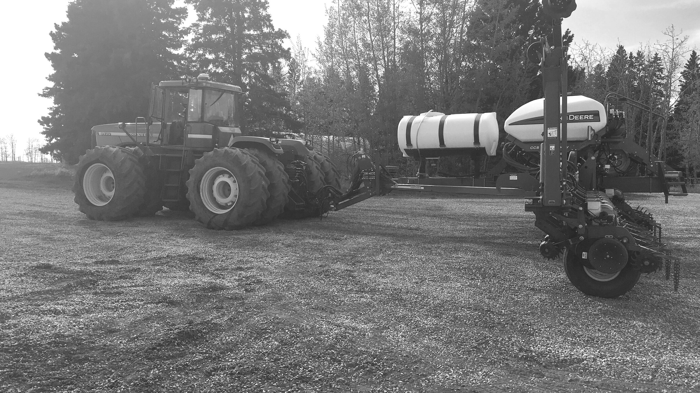 A four-wheel-drive tractor hitched to an air seeder, standing in a yard